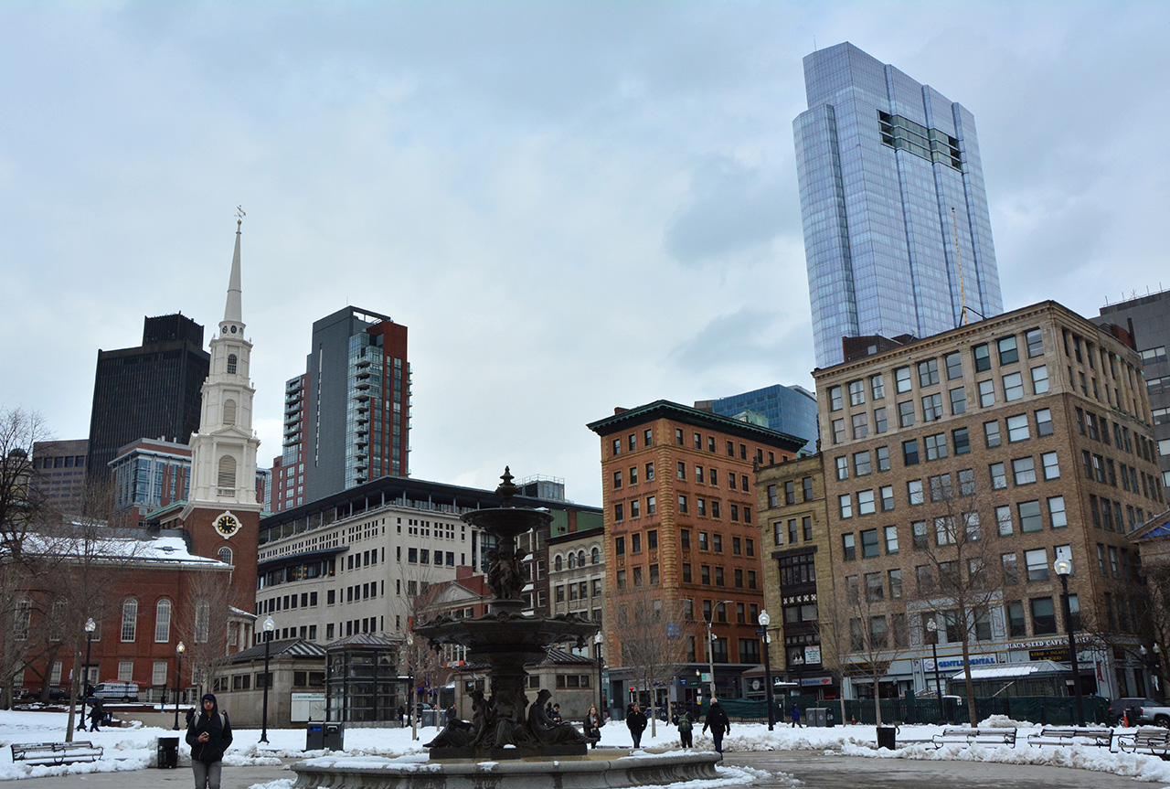 This image shows a fountain in Boston Common in the foreground, and in the background a skyline of tall buildings. The tallest and newest one stands out above the rest. It is Millennium Tower.