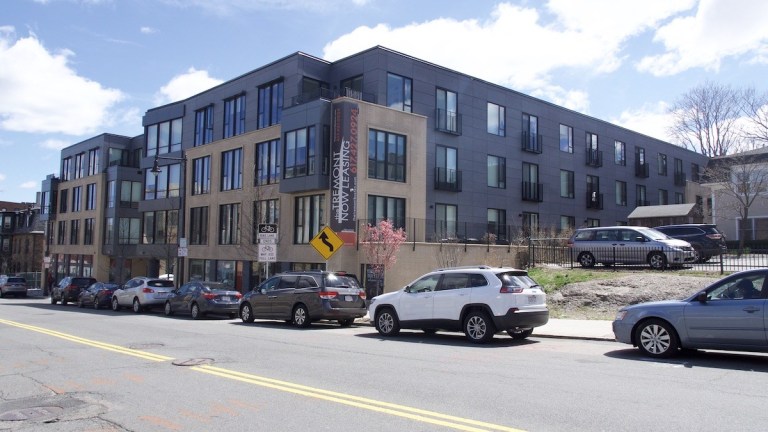 this image shows a street view of a large new condo development in Mission Hill, with cars parked in front.
