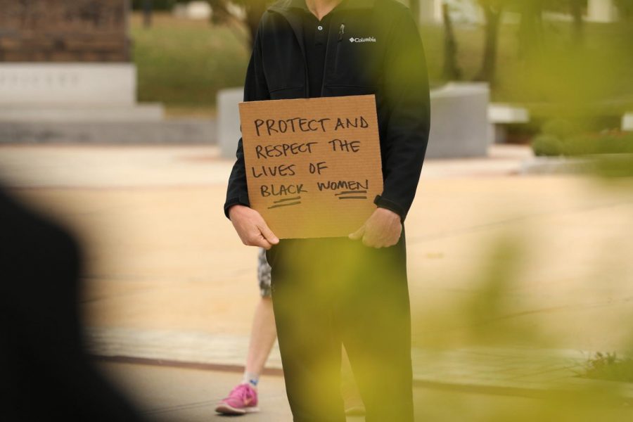 A protester holding a sign saying "Protect and respect the lives of Black women."