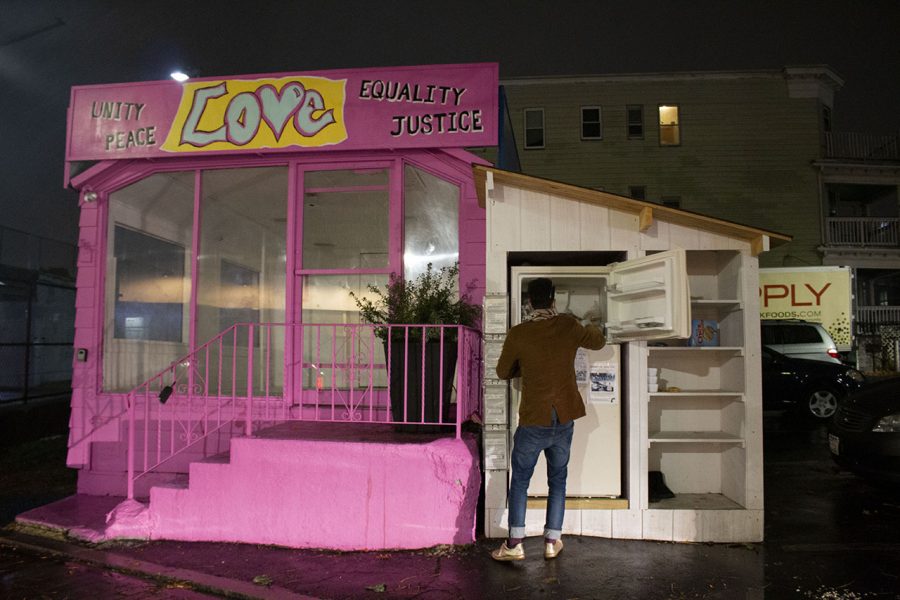 Abdella places packaged bread in the freezer of the Dorchester community fridge –– the first location to install shelving for dry goods