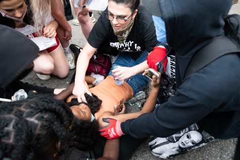 A woman lying on the street is tended to by other protesters after suffering the effects of peppers spray. The protesters were originally part of the Boston's first large protest following George Floyd's death but split from the march to continue protesting outside the station.