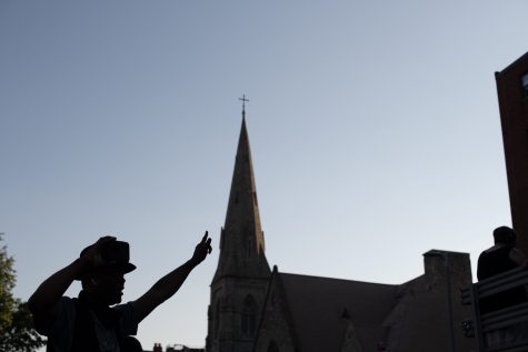 A man's dancing silhouette is caught against the former Tremont Street Methodist Episcopal Church as the Say Her Name March and Rally continues toward the Boston Common and into the evening0.
