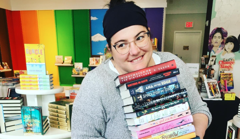 Christina Pascucci-Ciampa holds a stack of books in All She Wrote Books. 