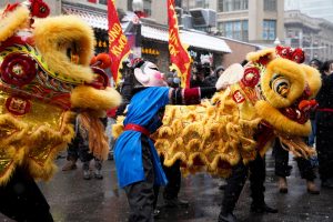 Two lions and a masked figure dance in the streets of Boston’s Chinatown during the lion dance parade. This year’s Lunar New Year rang in the Year of the Tiger on Sunday, Feb. 13, 2022.