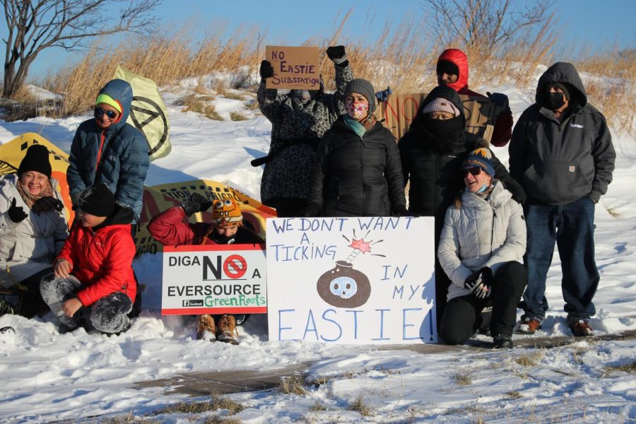 Protesters and East Boston residents pose for a photo at Condor Street Urban Wild with signs opposing the Eastie Substation on Sunday, Jan. 31, 2022.