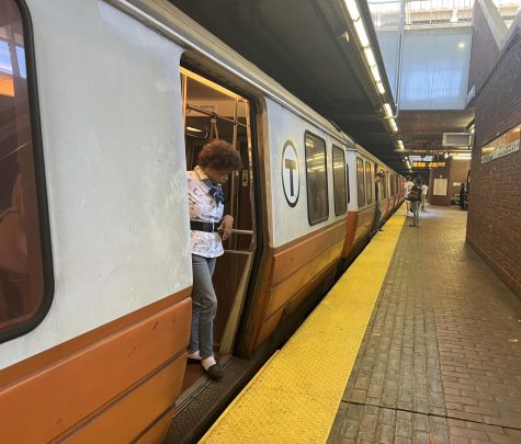 A woman steps out of a train at the Forest Hills stop