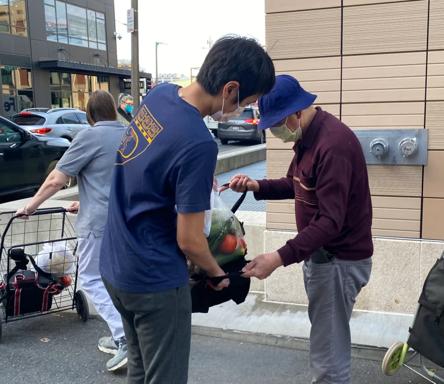 A volunteer helps an elderly man with groceries 