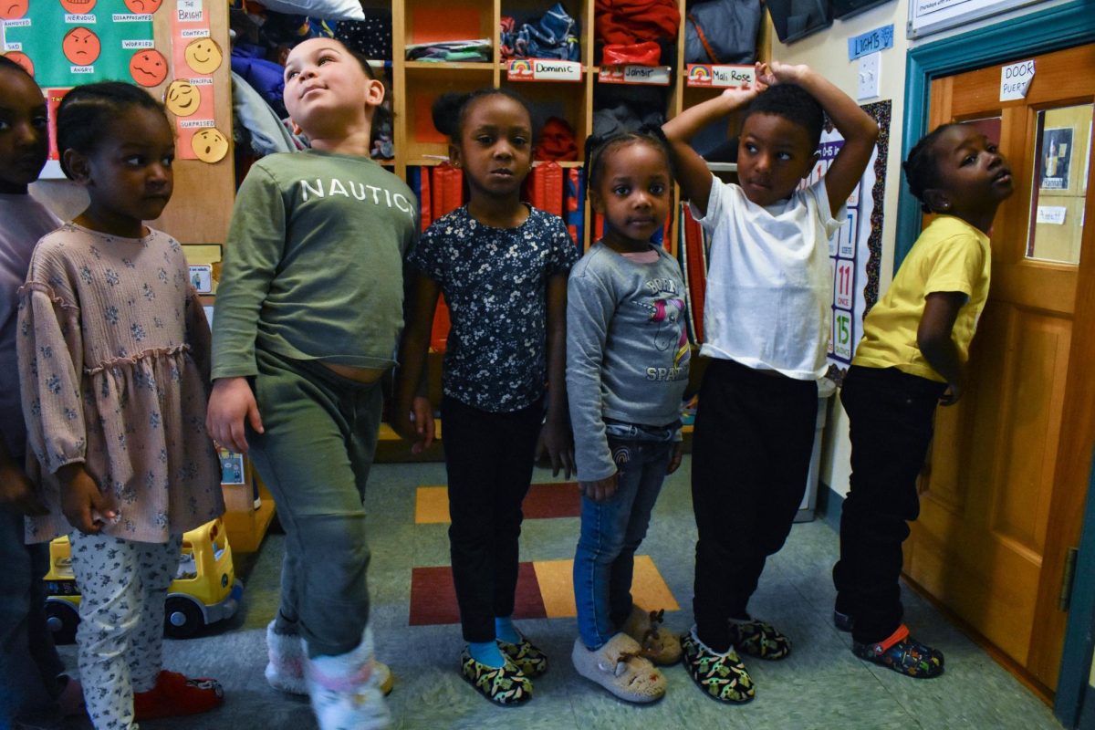 Boston, MA: April 4, 2023 - Preschool children line up for snack time while following the no shoe-rule at Paige Academy. 