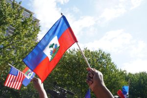 Protesters wave Haitian and American flags outside the Embrace Memorial on the Boston Common on Sept. 24, 2024. 