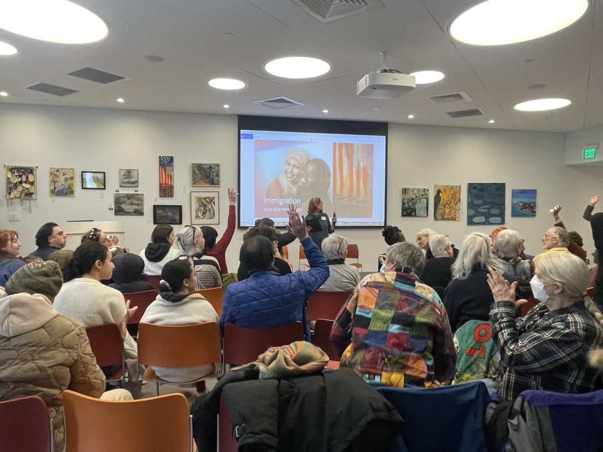 Exhibit-goers engage in discussion at opening reception of “Immigration: Joys and Hardships," an exhibit at Roslindale's library branch.